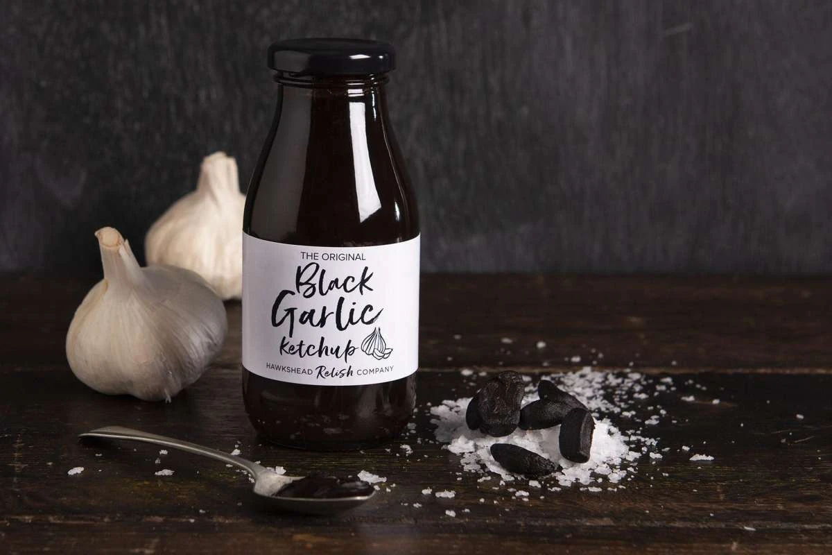 The Original Black Garlic Ketchup bottle with black garlic cloves and sea salt
